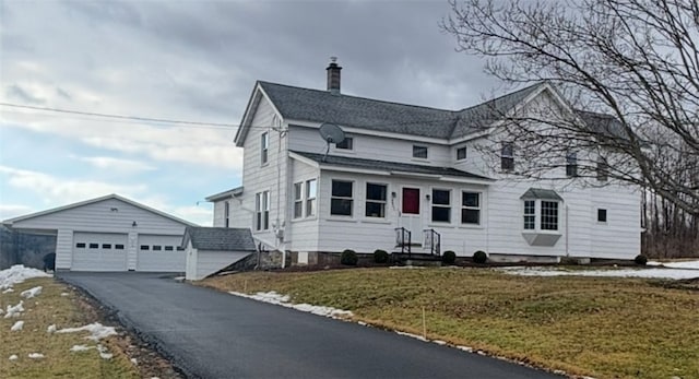 view of front facade with a chimney, entry steps, a garage, an outdoor structure, and a front lawn