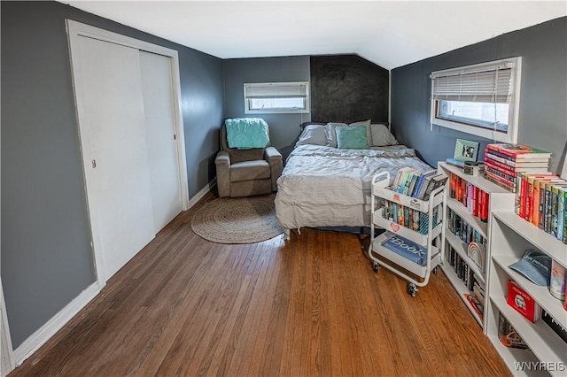 bedroom featuring multiple windows, baseboards, vaulted ceiling, and wood finished floors