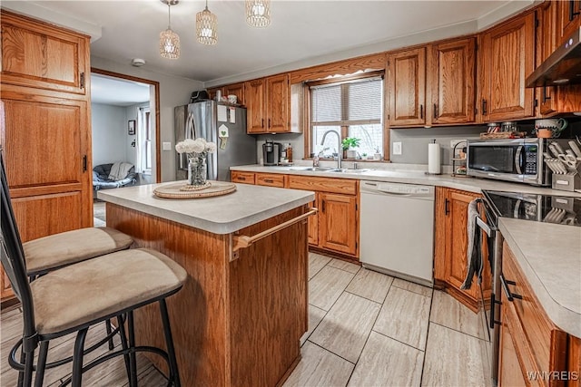 kitchen with under cabinet range hood, stainless steel appliances, a sink, light countertops, and brown cabinets