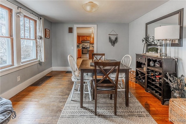 dining room featuring baseboards, visible vents, and wood finished floors