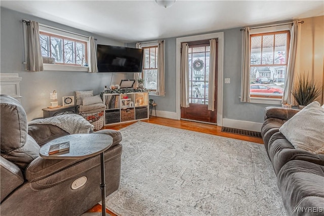 living room featuring wood finished floors, visible vents, and baseboards