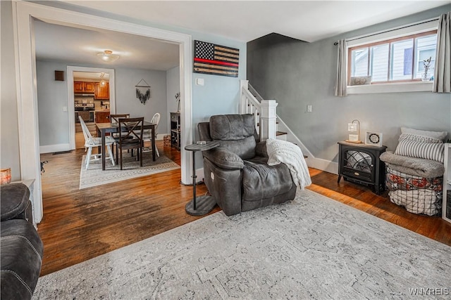 living area featuring stairs, baseboards, and wood finished floors