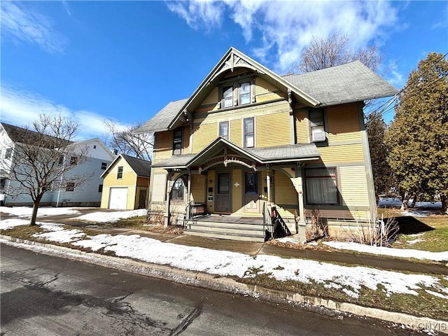 victorian house with covered porch, driveway, an outbuilding, and a garage