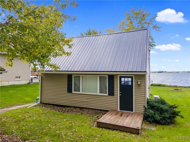 back of house with metal roof, a yard, and a water view