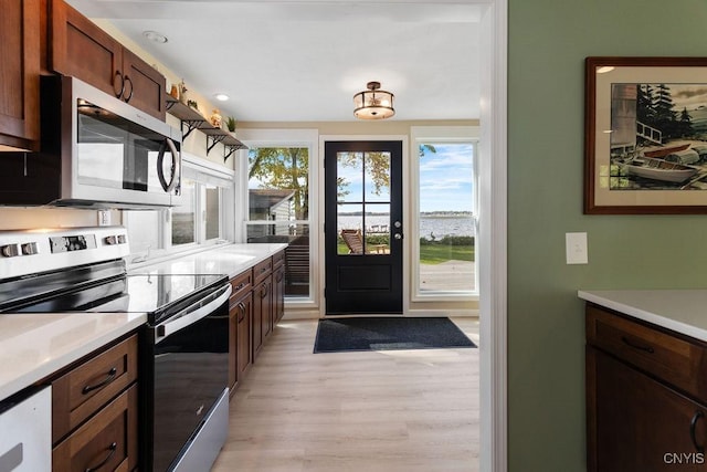 kitchen with light wood-type flooring, appliances with stainless steel finishes, and light countertops