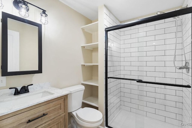 full bathroom featuring a shower stall, toilet, and vanity