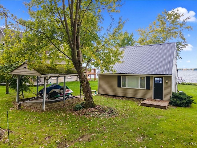 exterior space with a water view, metal roof, and a lawn