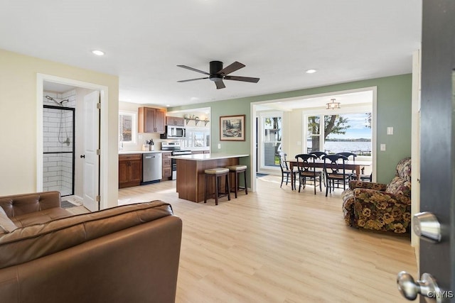 living area featuring recessed lighting, light wood-style flooring, and a ceiling fan