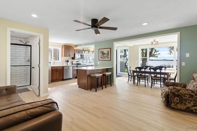 living area with ceiling fan, recessed lighting, a water view, and light wood-style floors