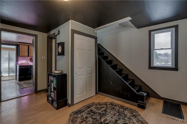 foyer with stairway, light wood-type flooring, visible vents, and baseboards