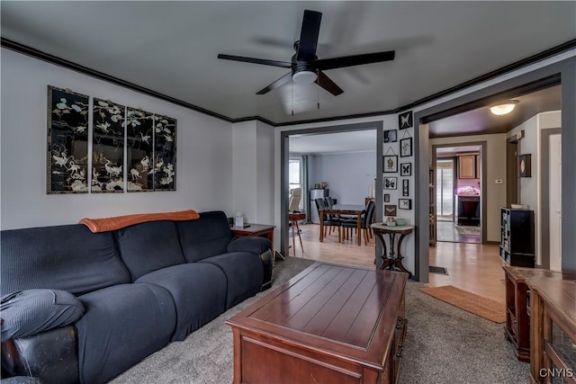 carpeted living area featuring ceiling fan and crown molding