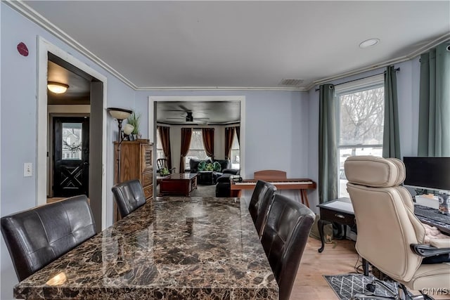 dining area with ornamental molding, visible vents, light wood-style floors, and ceiling fan