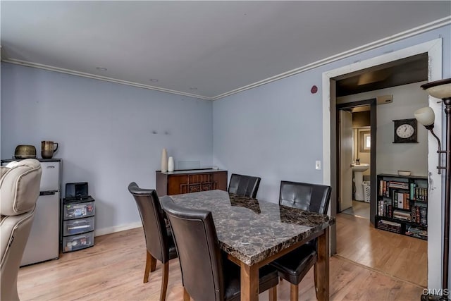 dining space with crown molding, light wood-style flooring, and baseboards