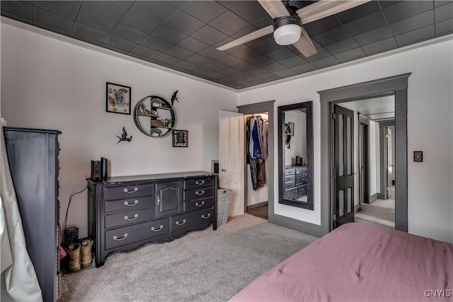 bedroom with a closet, a ceiling fan, a walk in closet, and carpet flooring