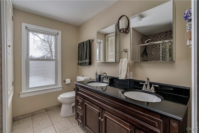 bathroom with a stall shower, a sink, toilet, and tile patterned floors