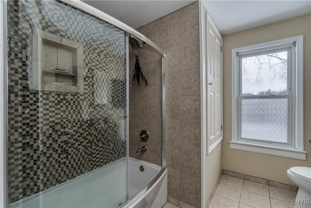 full bathroom featuring tile patterned flooring, toilet, and bath / shower combo with glass door