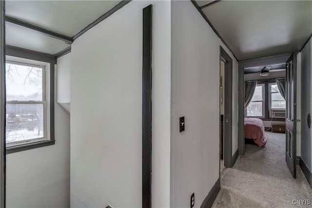 hallway with baseboards and light colored carpet