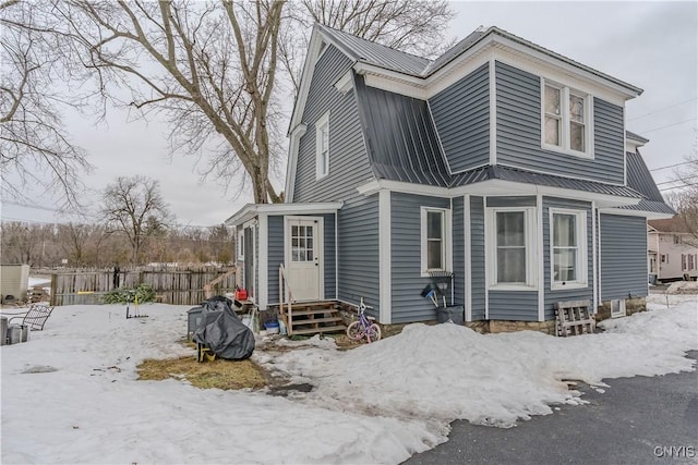 view of front of house featuring entry steps, metal roof, fence, and a gambrel roof