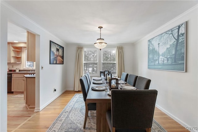 dining space featuring light wood-type flooring, baseboards, and crown molding