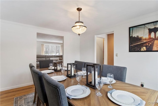 dining space with baseboards, a notable chandelier, wood finished floors, and crown molding