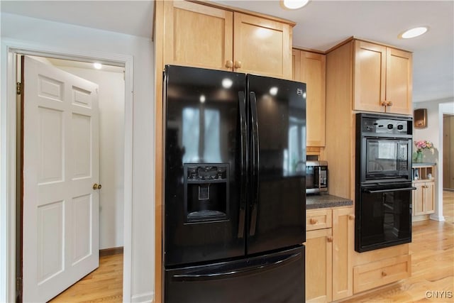 kitchen with dark countertops, light wood-style flooring, light brown cabinets, black appliances, and baseboards