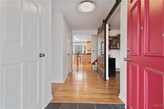 entryway with a barn door, wood finished floors, visible vents, baseboards, and stairs