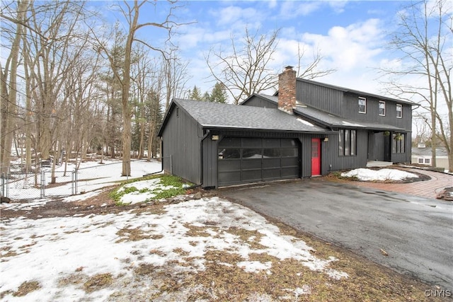 view of front of property with an attached garage, fence, driveway, roof with shingles, and a chimney