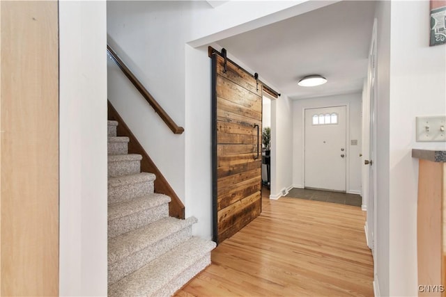 entrance foyer with light wood-type flooring, a barn door, and stairs