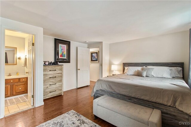 bedroom featuring a sink, connected bathroom, and dark wood-type flooring