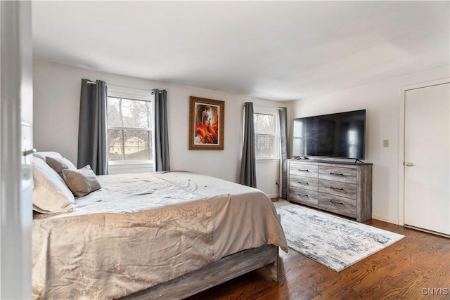 bedroom featuring multiple windows, baseboards, and wood finished floors