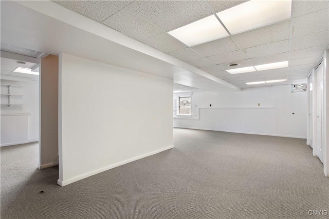 below grade area with carpet, baseboards, and a drop ceiling