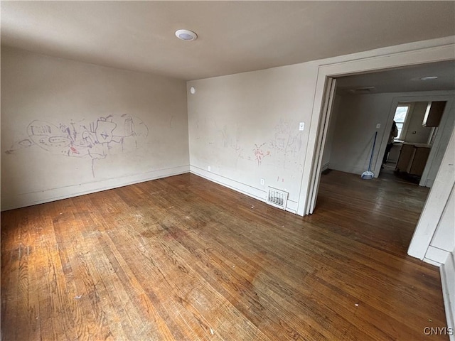 empty room featuring baseboards, visible vents, and hardwood / wood-style floors