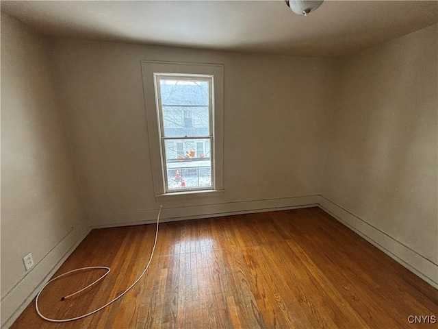 spare room featuring hardwood / wood-style floors, plenty of natural light, and baseboards