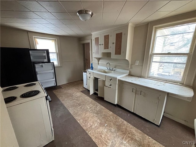 kitchen featuring white cabinets, white electric range oven, light countertops, and a sink