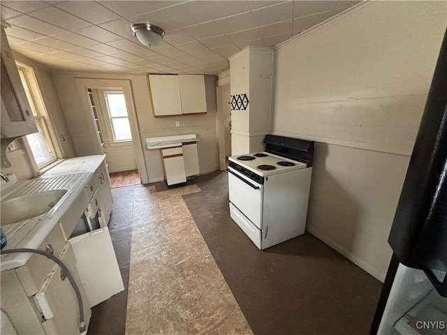 kitchen featuring light countertops, electric range, white cabinets, a sink, and baseboards