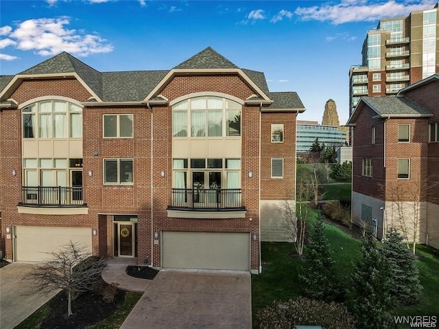 view of front of house with driveway, brick siding, an attached garage, and a shingled roof