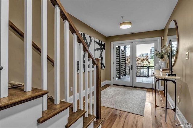 doorway with baseboards, stairway, wood finished floors, and french doors