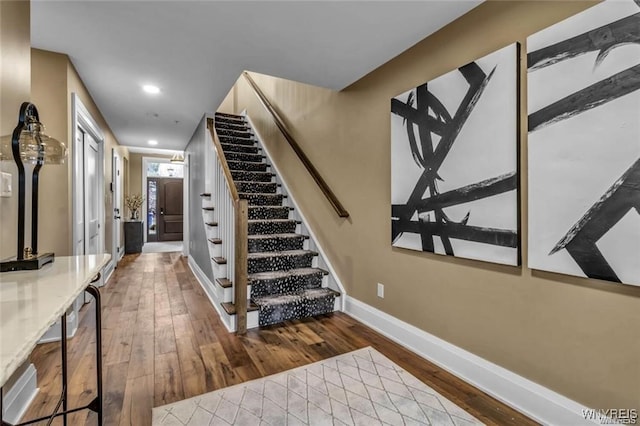 stairway featuring recessed lighting, hardwood / wood-style flooring, and baseboards