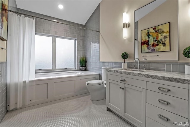 bathroom with toilet, a bathing tub, tile patterned floors, vanity, and tile walls