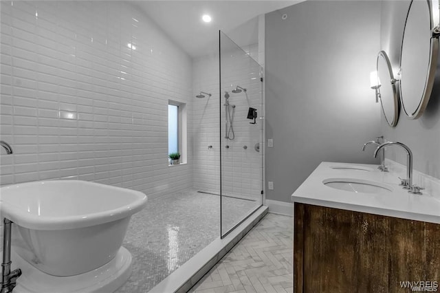 full bath featuring double vanity, a stall shower, a freestanding bath, a sink, and recessed lighting