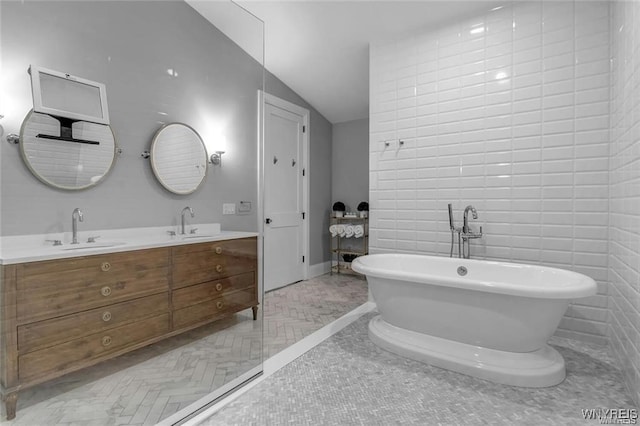 bathroom with double vanity, a freestanding bath, a sink, and lofted ceiling