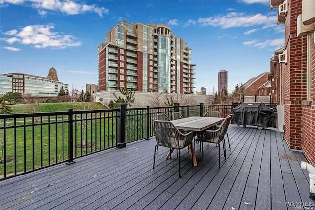 wooden deck with outdoor dining area, grilling area, and a yard