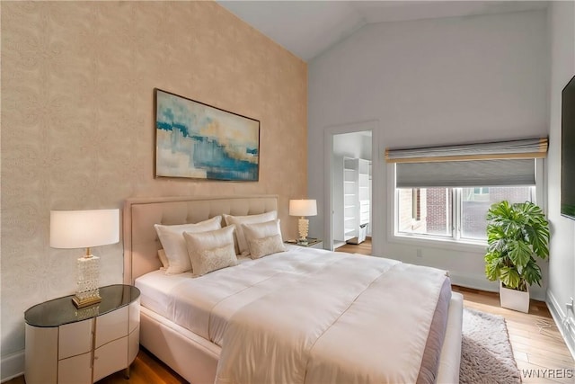 bedroom with vaulted ceiling, baseboards, and wood finished floors