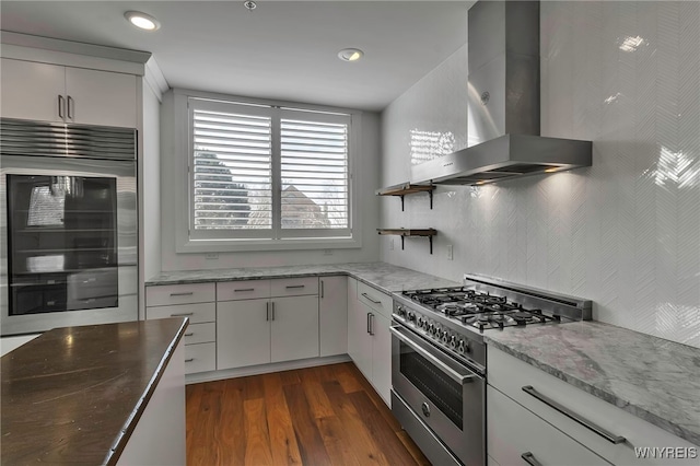 kitchen with stainless steel stove, open shelves, dark wood-style flooring, white cabinetry, and wall chimney exhaust hood