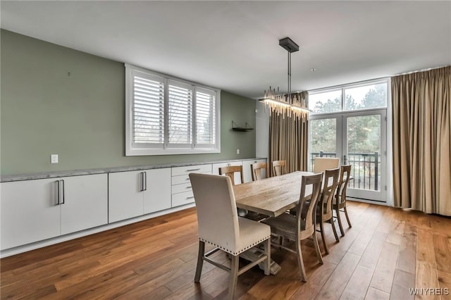 dining area with light wood finished floors, a wealth of natural light, and an inviting chandelier