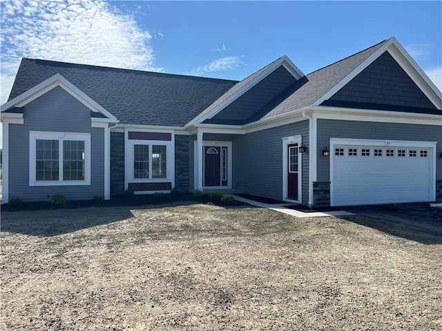 ranch-style home with a garage, stone siding, driveway, and roof with shingles