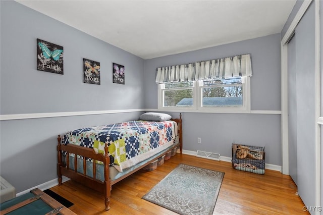 bedroom with wood finished floors, visible vents, and baseboards