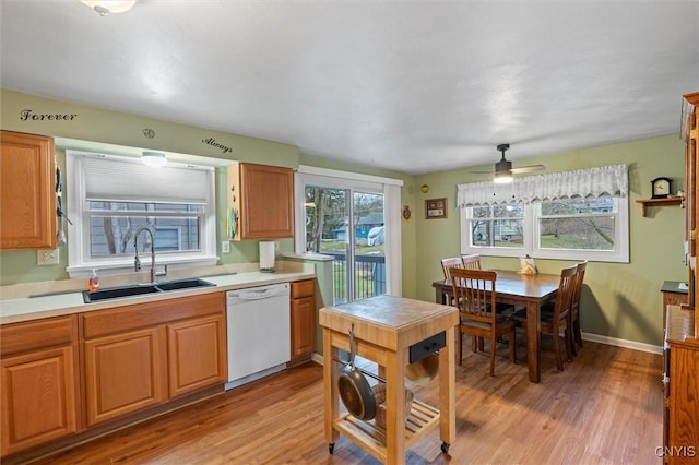 kitchen with light wood-type flooring, light countertops, dishwasher, and a sink