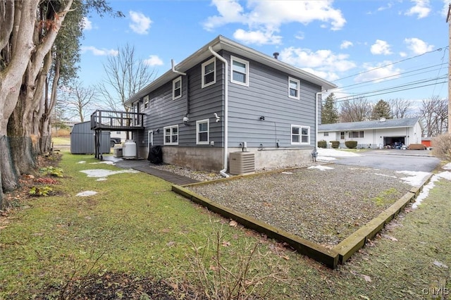 view of home's exterior featuring driveway, a lawn, an outbuilding, fence, and cooling unit