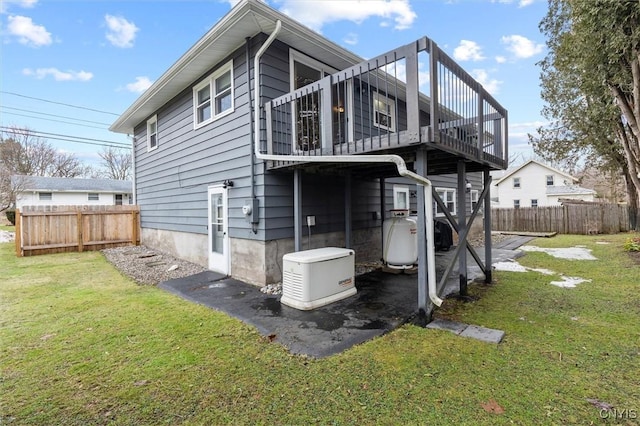 back of house with a deck, a lawn, and fence